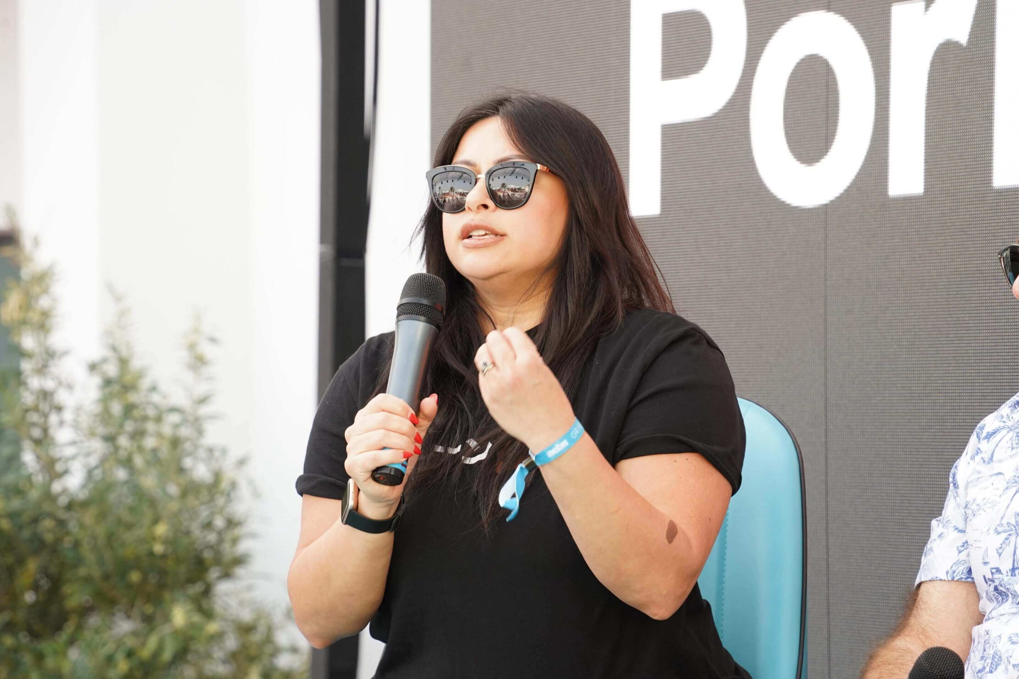 Woman in sunglasses speaking into microphone